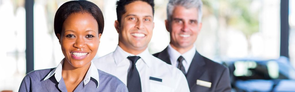 professional dealership team standing together in a modern car showroom, representing customer service and automotive expertise.